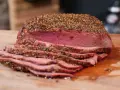 Perfekt gegarter Roastbeef Braten, saftig und rosa, mit einer würzigen Kruste aus Pfeffer und Kräutern, auf einem Holzbrett.