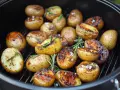 Gegrillte Rosmarinkartoffeln mit grobem Salz und Kräutern auf einem Rost.