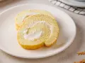 Zwei Scheiben einer saftigen Zitronenrolle mit cremiger Füllung auf einem Teller. Ein einfaches, aber köstliches zitronenrolle rezept.