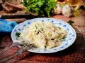 Ein Teller mit Krautsalat, garniert mit Petersilie. Daneben liegen Gabel und Löffel. Ein leckeres Krautsalat Rezept für dich!