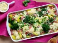 Ein herzhafter Blumenkohl-Brokkoli-Auflauf mit Kartoffeln und Schinken, bestreut mit frischer Petersilie und Käse.