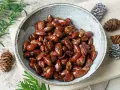 Schüssel mit glasierten, gebrannten Mandeln, zubereitet im Airfryer. Dekoriert mit Tannenzapfen und Tannenzweigen.