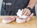 Vorbereitung für ein saftiges Kotelett Rezept: Frische Schweinekoteletts werden auf einem Holzbrett mit Küchenpapier abgetupft.