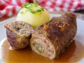 Herzhaftes Rouladen Rezept: Zarte Rinderrouladen mit Kartoffelklößen in einer kräftigen Soße, garniert mit Petersilie.