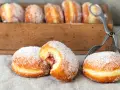 Zuckerüberzogene Berliner, eines davon mit Marmeladenfüllung, warten auf das nächste berliner rezept.