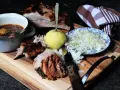 Deftige dicke Rippe mit Klößen, Sauerkraut und dunkler Soße auf Holzbrett.
