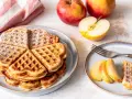 Herzförmige Waffeln mit Puderzucker, daneben frische Äpfel und Apfelspalten. Ein Genuss für alle Sinne!