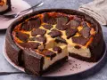 Ein saftiger russischer Zupfkuchen mit dunklem Schokoladenboden und cremiger Käsemasse, belegt mit zupfartigen Schokoladenstückchen.