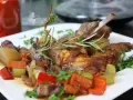 Klassisches Kaninchen-Rezept: Zartes Kaninchen mit Wurzelgemüse und Rosmarin auf einem weißen Teller serviert.