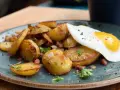 Bratkartoffeln mit Speck und einem Spiegelei, ein klassisches Rezept für ein herzhaftes Frühstück oder Abendessen.