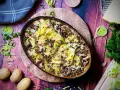 Herzhafter kartoffelauflauf mit hackfleisch, überbacken mit Käse und garniert mit Petersilie. Dazu frische Kartoffeln, Lauch und ein Stück Käse.