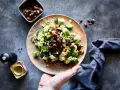 Frischer Brokkoli Salat mit Nüssen und roten Zwiebeln auf einem Holzteller, bereit zum Genießen.