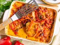 Herzhaftes Paprika Sahne Schnitzel in einer Auflaufform, mit roten Paprikastreifen und Zwiebeln in cremiger Sauce.