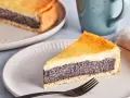 Ein Stück Mohn Schmand Kuchen mit goldbraunem Boden und cremiger Füllung auf einem Teller, daneben eine Tasse.