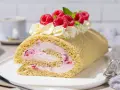 Himbeer Biskuitrolle mit Sahne und frischen Beeren, ein Genuss für jeden Kaffeetisch.