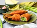 Knusprig paniertes Spargel Cordon Bleu mit Schinken und Käse gefüllt, auf einem grünen Teller angerichtet.