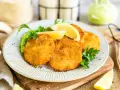 Knuspriges Kohlrabi Schnitzel auf einem Teller mit Erbsenpüree, Zitrone und Petersilie. Ein Genuss für Vegetarier!