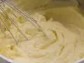 Cremiger kartoffelbrei ohne butter wird mit einem Schneebesen in einem Topf zubereitet.