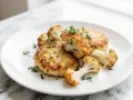 Knusprige Blumenkohl Schnitzel auf einem Teller, garniert mit frischer Petersilie. Ein leckeres vegetarisches Gericht.