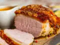 Saftiger Braten mit knuspriger Kruste, perfekt für die Zubereitung von Prager Schinken im Backofen. Dazu eine Schüssel mit Sauce.