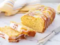 Saftiger zitronenkuchen mit Joghurt, überzogen mit Zuckerguss und garniert mit Zitronenschale. Ein Stück ist angeschnitten.