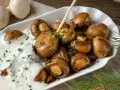 Herzhafte Champignons wie vom Weihnachtsmarkt, glasiert und mit Kräutern bestreut, serviert mit cremiger Sauce.