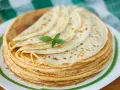 Ein Stapel goldbrauner Pfannkuchen, wie nach Omas Pfannkuchen Rezept gemacht, mit einem Minzblatt garniert.