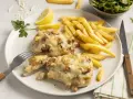 Zwei saftige Steak au Four mit geschmolzenem Käse, dazu knusprige Pommes Frites, Zitronenspalten und ein kleiner Salat.