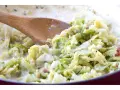 Cremiger Wirsing mit Speck, zubereitet mit einem Holzlöffel. Ein leckeres Gericht, das Lust auf mehr wirsing rezepte macht.