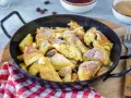 Leckerer, schneller Kaiserschmarrn im Backofen, bestäubt mit Puderzucker und Rosinen, serviert in einer Pfanne.