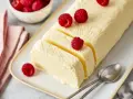 Cremiger Rhabarber Pudding, dekoriert mit frischen Himbeeren, auf einem Teller mit Löffeln.
