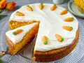 Ein saftiger Karottenkuchen mit weißem Frosting und kleinen Marzipanmöhren, perfekt für ein Osterkuchen Rezept.