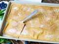 Großer, goldbrauner Ofenpfannkuchen mit Zucker und Zimt bestreut, bereit zum Servieren. Blaubeeren und Minze garnieren.