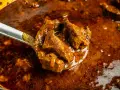 Ein Löffel voller herzhaftem Wildschweingulasch, bereit zum Servieren. Dieses Wildschweingulasch Rezept verspricht ein köstliches Gericht.