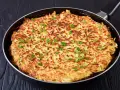 Goldbraune Kartoffel-Rösti in einer Pfanne, garniert mit Petersilie. Ein einfaches und leckeres schales Rezept für jeden Tag.