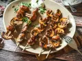 Gegrillte Champignons am Spieß, mit Kräutern verfeinert, auf einem Teller serviert. Ein Genuss für jeden Pilzliebhaber!