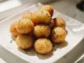 Goldbraune, knusprige kroketten aus kartoffelbrei, garniert mit Petersilie, auf einem weißen Teller.
