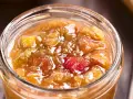 Ein Glas mit leuchtend rotem und goldenem Rhabarber-Chutney, bereit zum Genießen.