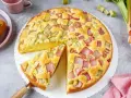 Saftiger Rhabarberkuchen, ein Klassiker unter den Rezepten mit Rhabarber. Ein Stück wird gerade herausgehoben.