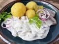 Marinierter Hering in cremiger Soße mit Salzkartoffeln, Gurken und Zwiebelringen. Ein deftiges Gericht, das Appetit macht.