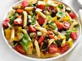 Bunter Nudelsalat ohne Mayo mit Penne, gegrilltem Gemüse, Kirschtomaten und Basilikum, garniert mit Parmesan.