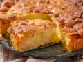 Ein Stück von einem goldbraunen, sehr feinen Apfelkuchen mit Zimt bestreut, wird mit einer Tortenheber herausgehoben.