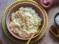 Cremiger Milchreis, bestreut mit Zimt, wartet in einer Schale auf sein Milchreis Rezept. Daneben liegen Reiskörner und Zimtstangen.