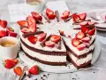 Eine köstliche Yogurette Torte mit frischen Erdbeeren und Schokostückchen, serviert mit einer Tasse Kaffee.