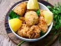 Knuspriger blumenkohl im airfryer, goldbraun paniert, serviert mit frischen Zitronenspalten und Petersilie.