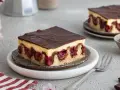 Ein Stück Donauwelle ohne Buttercreme, mit dunkler Schokoladenglasur, Kirschen und hellem Teig.