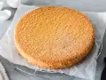 Ein goldbrauner, luftiger Biskuitboden auf Backpapier, bereit für ein köstliches Biskuitboden Rezept.