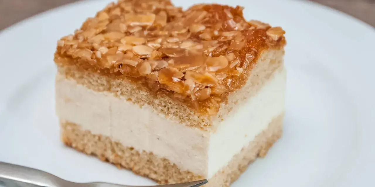 Ein Stück Bienenstich-Kuchen mit cremiger Füllung und karamellisierten Mandeln. Perfekt für das Bienenstich Rezept!
