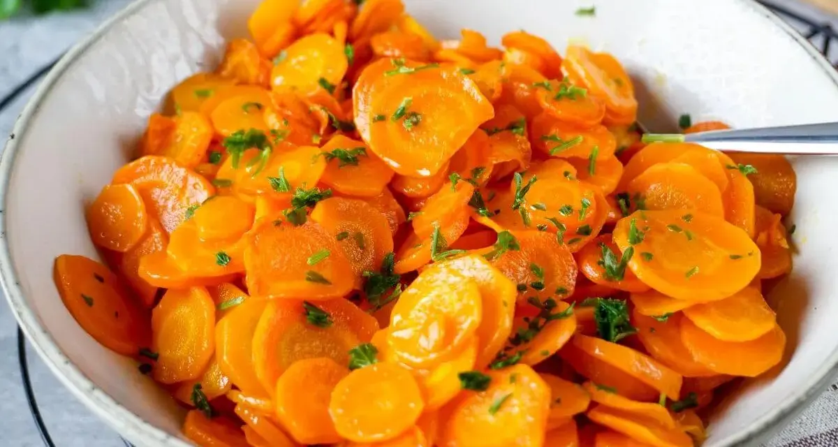 Schüssel mit glasierten Karottenscheiben, garniert mit Petersilie. Perfekt gekochte Karotten, die Lust auf mehr machen.