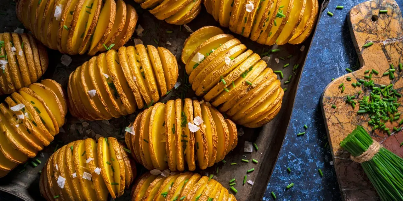 Fertig gegrillte Hasselback-Kartoffeln mit Schnittlauch und grobem Salz, bereit für den Gasgrill.
